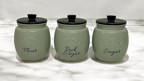 Green canisters with custom labels for flour, rock sugar, and sugar add a stylish touch to kitchen storage.